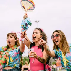 Tres chicas con camisas tropicales y collares de flores, riendo y bailando. ¡Me encanta el espíritu de las tuenti's!