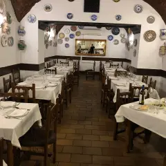Mesas puestas en el restaurante La Troya Trujillo, decorado con platos de cerámica en las paredes.