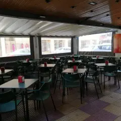 Terraza de bar con mesas y sillas verdes, ideal para saber donde comer en Cullera bien y barato.