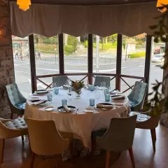 Mesa elegante lista para una cena en la corte de Pelayo, con vistas a la calle y un parque.