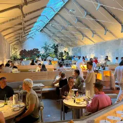 Gente cenando en un moderno espacio tramo Madrid, con techos altos y luz natural.