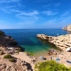 Un día soleado en el racó del conill, con gente disfrutando de las aguas cristalinas y la arena dorada.