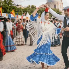 Pareja bailando flamenco en las fiestas de Alcobendas. Ella, con vestido de lunares y mantón de flecos; él, con chaleco y gorra.