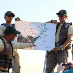 Guías explican un mapa de la Amazonía, compartiendo valiosas opiniones de restaurante amazónico para una aventura inolvidable.
