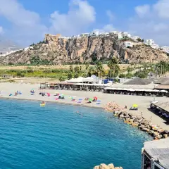 Vista de las playas de Salobreña con gente disfrutando del sol y el mar. El castillo de Salobreña corona la colina.