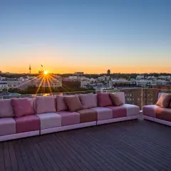 Sofás modulares rosas en una terraza con vistas a la ciudad al atardecer. Una casa suecia rooftop perfecta para disfrutar del sol.