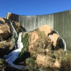 Cascada en la presa de Elche, un lugar ideal para una ruta pantano elche. El agua cae sobre rocas cubiertas de musgo y vegetación.