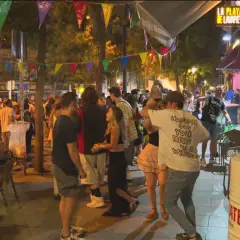 Gente disfrutando de las fiestas de San Lorenzo en Madrid, con luces, música y ambiente festivo en la calle.
