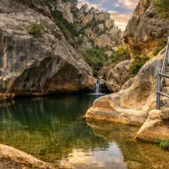 Un remanso de paz entre rocas, con una cascada y escaleras que invitan a explorar los **ríos en Tarragona**.