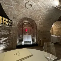 Menú de la Bodega de los Secretos en un ambiente rústico con arcos de piedra y mesas preparadas.