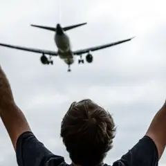 Persona con brazos en alto celebra la llegada de un avión en el mirador de aviones de El Prat.