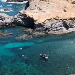 La cala Medina en Cabo de Palos, con aguas cristalinas y una pequeña embarcación, invita a explorar sus secretos.