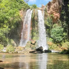 Cascada imponente cayendo en el lago de Anna, rodeada de vegetación exuberante y rocas cubiertas de musgo.