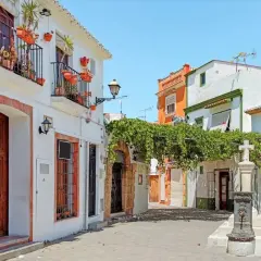 Callejuela con casas blancas, balcones floridos y una fuente. Así es donde está Denia, un rincón con encanto.