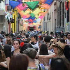 Gente bailando en las fiestas San Cayetano Madrid, con coloridas telas adornando la calle.