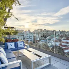 Terraza del Ginkgo restaurante & sky bar con vistas a la ciudad al atardecer. Sofás azules y mesa de centro.