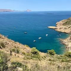Vista panorámica de la cala de la mina, con aguas turquesas y barcos navegando.