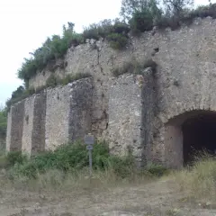 Antigua construcción de piedra en la Serra de Mariola, con un arco de entrada y vegetación circundante.
