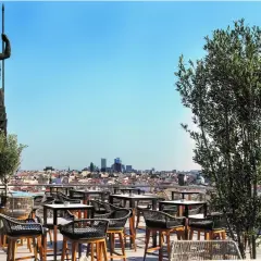 Terraza Bellas Artes Madrid con vistas a la ciudad, una estatua imponente y mesas listas para disfrutar.