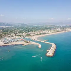 Vista aérea de la playa de Oliva, con su puerto deportivo, arena dorada y aguas turquesas. Las opiniones sobre la playa de Oliva son muy positivas.