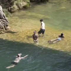 Gente disfrutando de un día en las playas cerca de Zaragoza, nadando y refrescándose en aguas cristalinas.