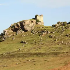 Ruinas de un castillo en una colina rocosa, un paisaje que evoca la historia de Navas de Tolosa, donde está.