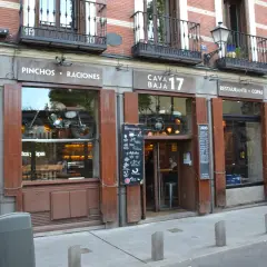 Fachada de Cava Baja 17, un restaurante con una moto vintage expuesta en el escaparate.