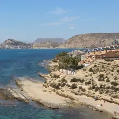 Vista de la cala Cantalar en Alicante, con casas en la ladera y el mar azul.