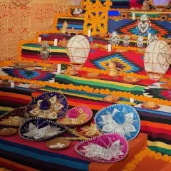 Un vibrante altar de los muertos en una casa de México, adornado con sombreros, flores de cempasúchil y ofrendas.