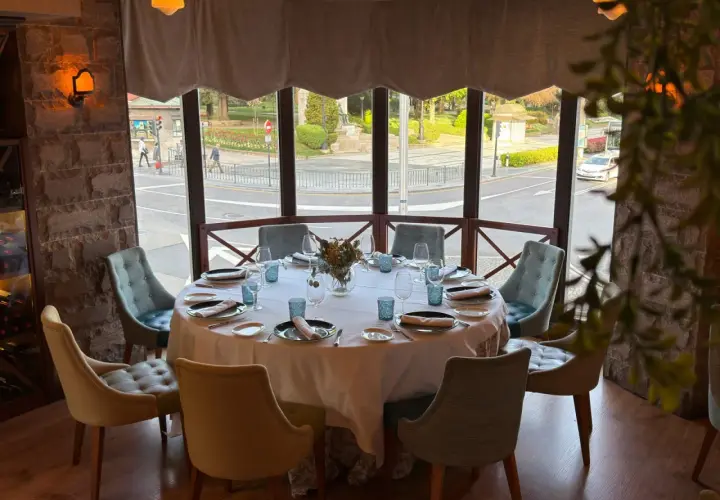 Mesa elegante lista para una cena en la corte de Pelayo, con vistas a la calle y un parque.