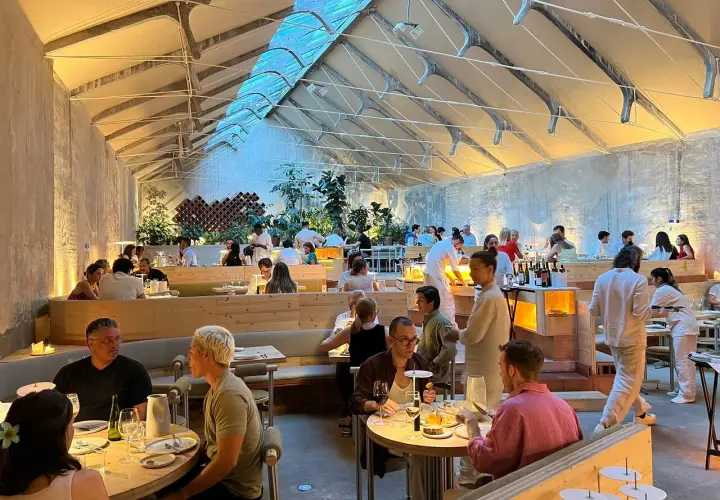 Gente cenando en un moderno espacio tramo Madrid, con techos altos y luz natural.