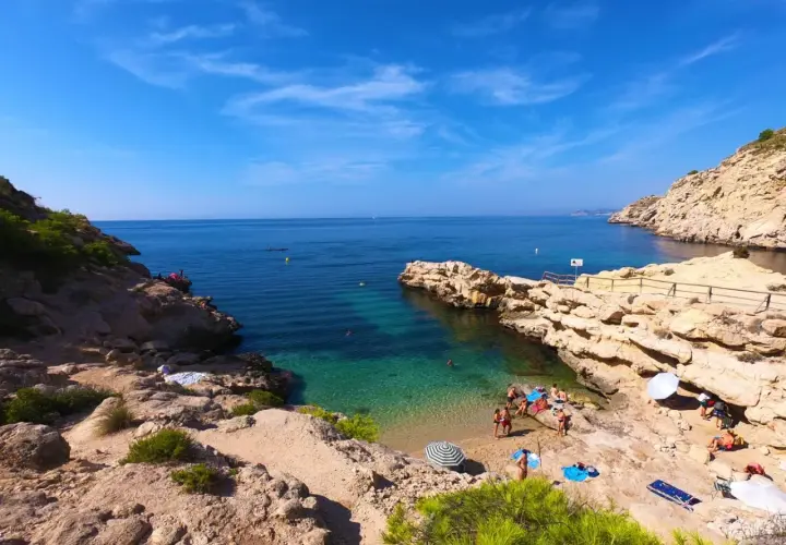 Un día soleado en el racó del conill, con gente disfrutando de las aguas cristalinas y la arena dorada.