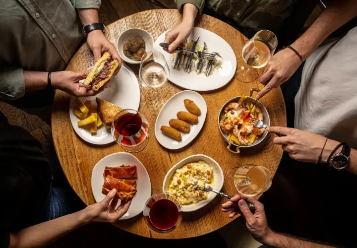 Amigos disfrutan tapas variadas: sándwich, croquetas, sardinas, gambas y pastel salado. ¡Un festín para saber donde comer bien y barato en Talavera de la Reina!