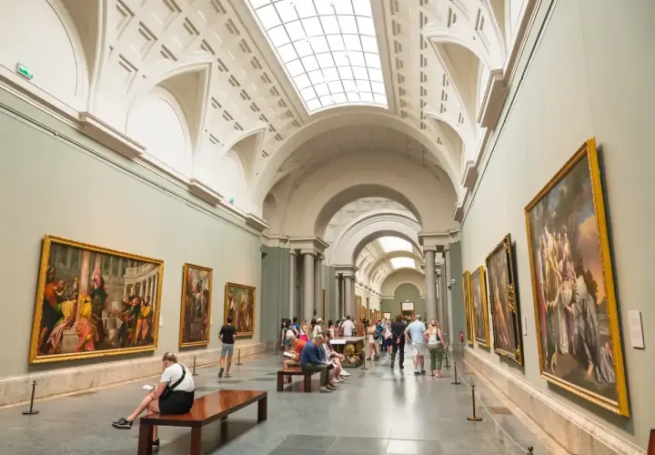 Gente disfruta del arte en un museo, celebrando el **18 de mayo, Día de los Museos**.