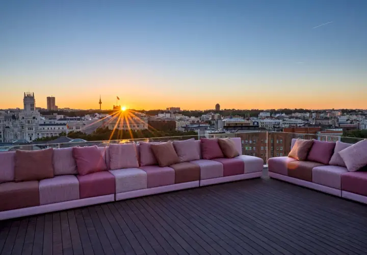 Sofás modulares rosas en una terraza con vistas a la ciudad al atardecer. Una casa suecia rooftop perfecta para disfrutar del sol.
