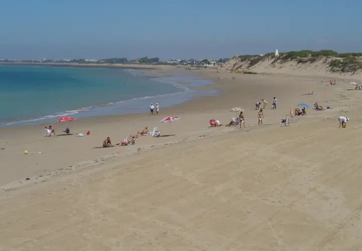 Gente disfruta del sol en la playa de Punta Candor, Rota. ¡Un lugar ideal para relajarse y leer opiniones positivas!