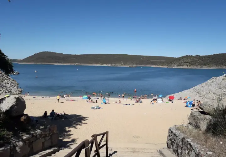 Gente disfrutando del sol y el agua en la playa fluvial de Ricobayo, un día perfecto para refrescarse.