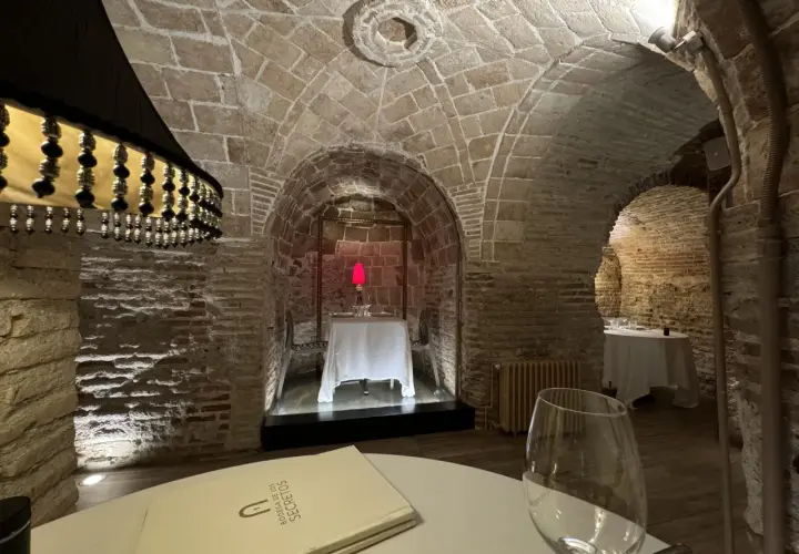 Menú de la Bodega de los Secretos en un ambiente rústico con arcos de piedra y mesas preparadas.
