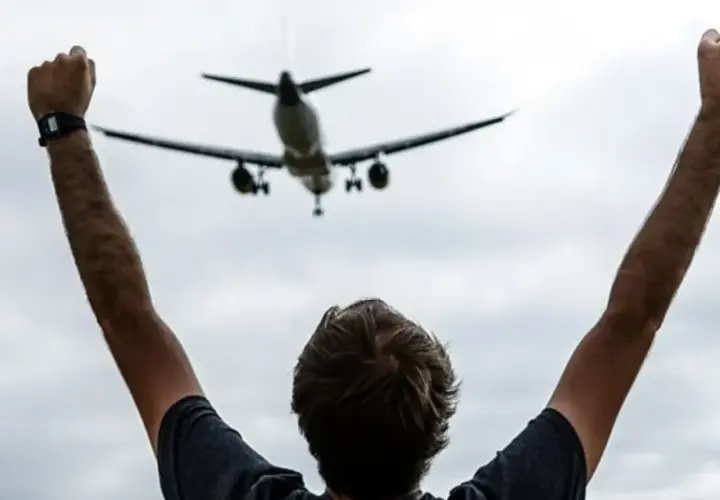 Persona con brazos en alto celebra la llegada de un avión en el mirador de aviones de El Prat.