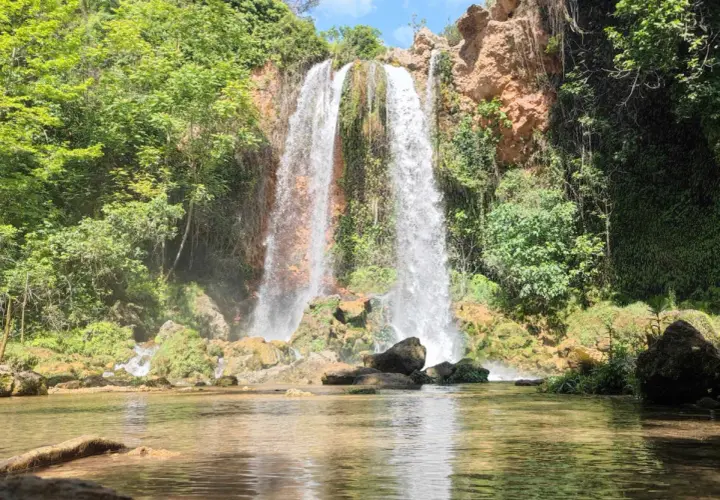 Cascada imponente cayendo en el lago de Anna, rodeada de vegetación exuberante y rocas cubiertas de musgo.