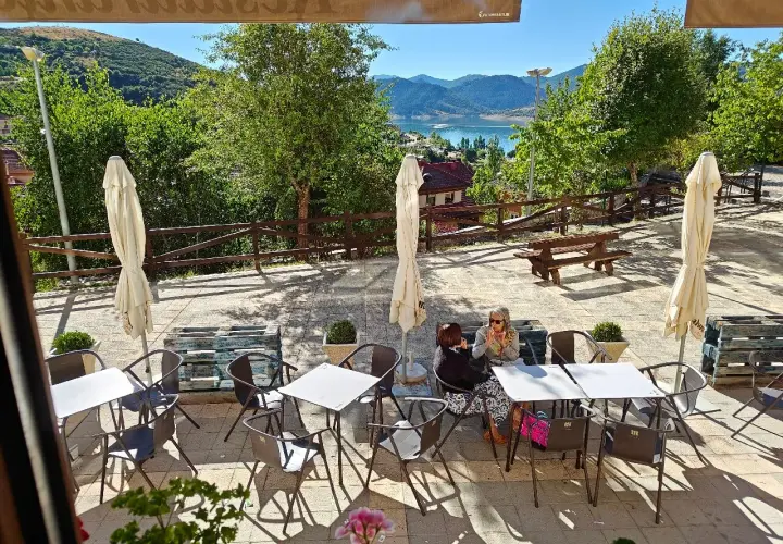 Terraza de restaurante con vistas al embalse. Ideal para saber donde comer en Riaño. Mesas, sillas y sombrillas listas para disfrutar.