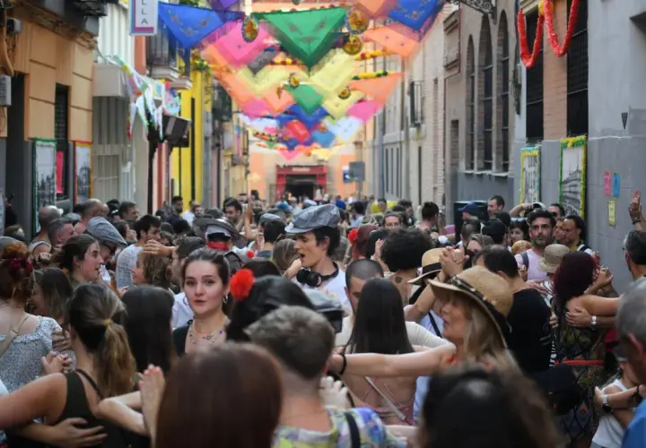 Gente bailando en las fiestas San Cayetano Madrid, con coloridas telas adornando la calle.