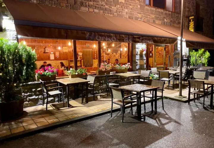 Restaurante "Horno de Lena" en Broto, con mesas al exterior y gente cenando. Ideal para saber donde comer en Broto.