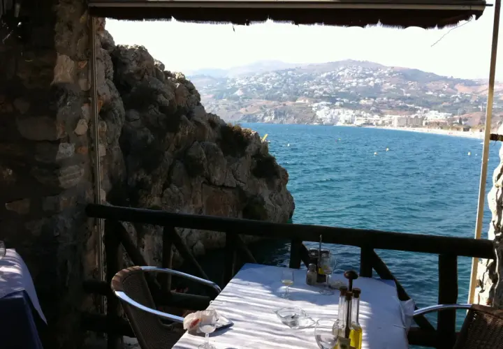 Mesa en restaurante el peñón con vistas al mar. Las reseñas destacan su ubicación privilegiada y la experiencia culinaria.