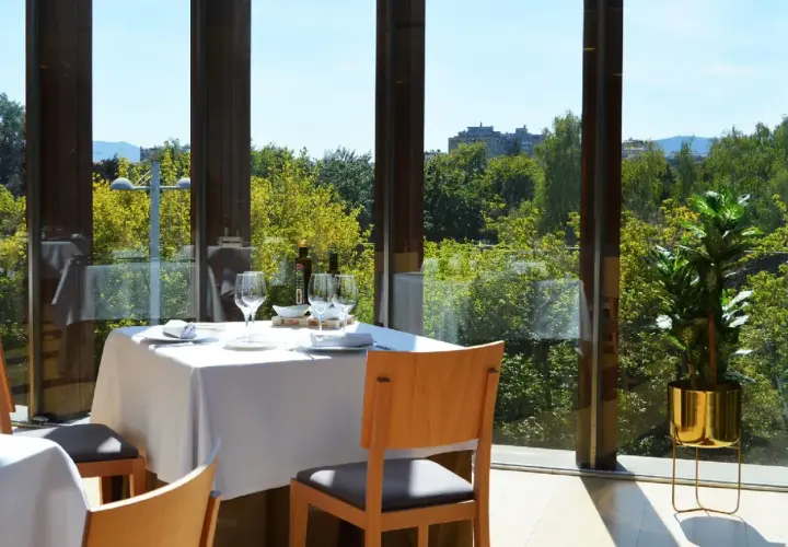Elegante mesa puesta en un restaurante con vistas a la naturaleza, ideal para descubrir los mejores restaurantes en pueblos cerca de Pamplona.