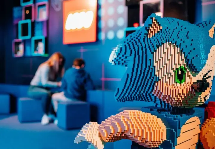 Figura de Sonic hecha de LEGO en el museo LEGO de Madrid. Al fondo, dos personas observan una exposición.