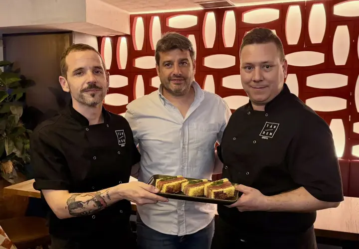 Tres hombres posan con un plato de aperitivos en un mesón. Las fotos capturan el momento.