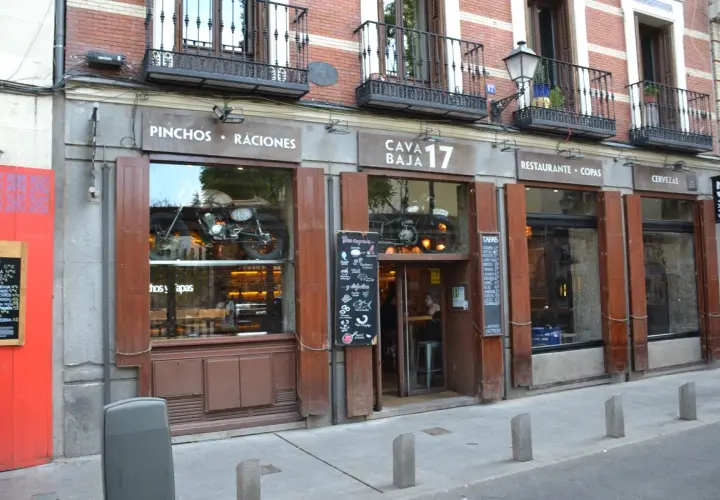 Fachada de Cava Baja 17, un restaurante con una moto vintage expuesta en el escaparate.