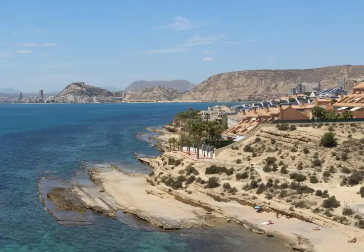 Vista de la cala Cantalar en Alicante, con casas en la ladera y el mar azul.