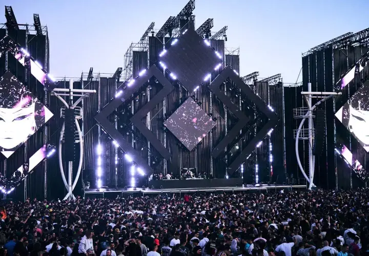 Multitud vibrante en un festival de música, escenario futurista con luces y pantallas. Una escena épica para tu summer story 2026.